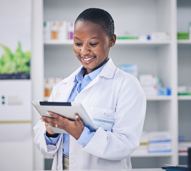 Pharmacist in a white lab coat using a tablet to research medications for patients.
