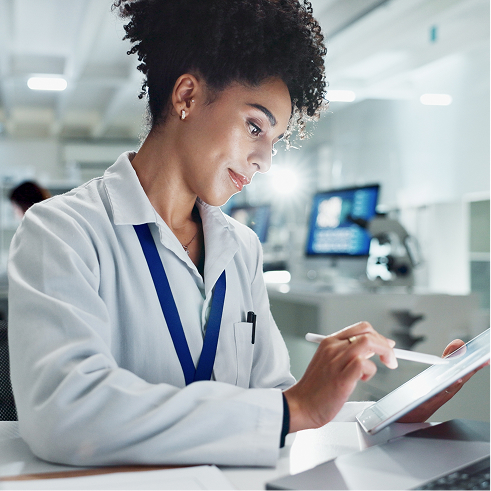 Pharmacist in a white lab coat using a tablet and stylus to order medications for patients.